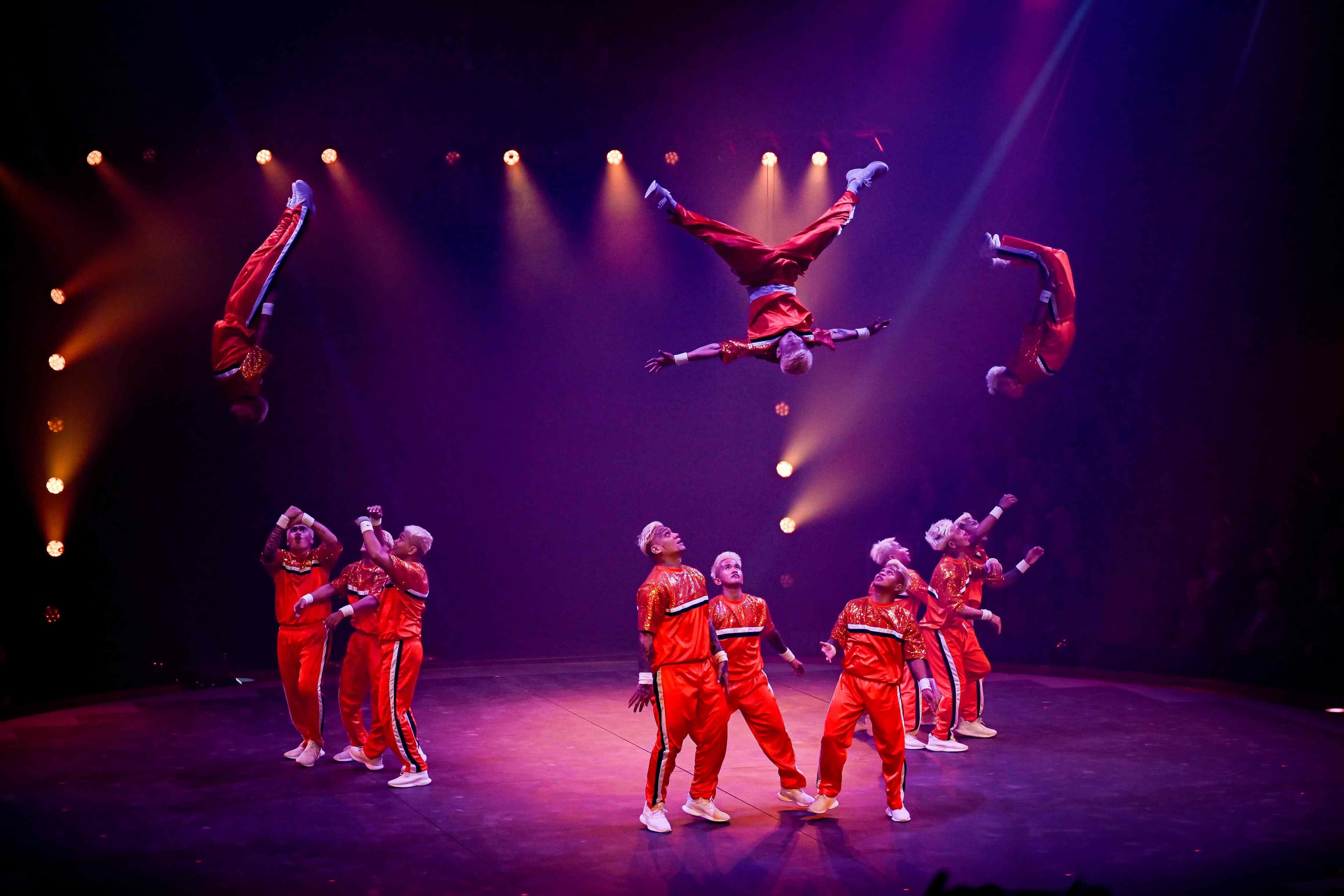 Artisten in roten Trainingsanzügen springen und fliegen über die Bühne im Circus Knie