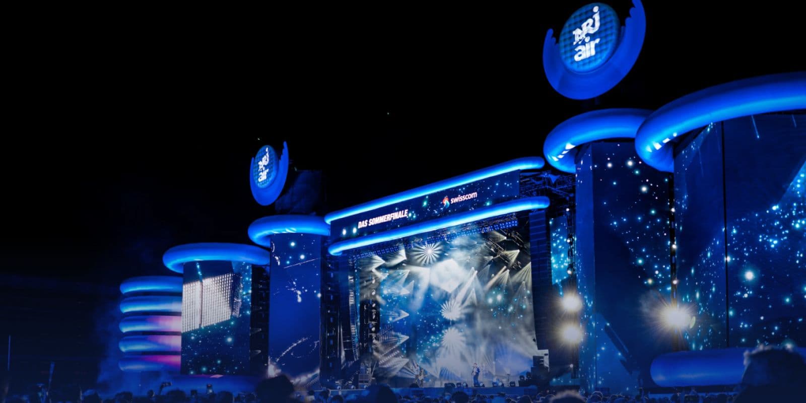 Blau beleuchtete ENERGY AIR Bühne mit NRJ-air-Logos bei Nacht